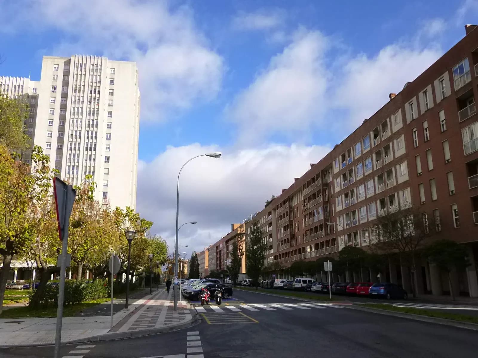 Avenida de Barañáin con bloques de viviendas de ladrillo, árboles en la acera y una torre alta de viviendas al fondo