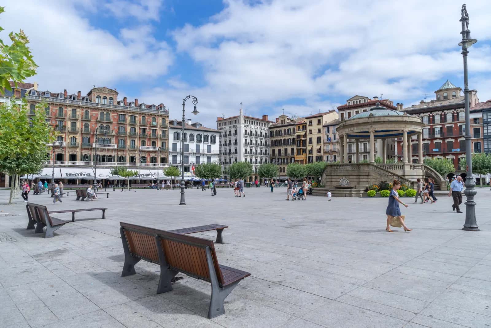 Plaza del Castillo de Pamplona con su quiosco, bancos de madera y edificios de varias plantas con balcones alrededor, entre ellos el Gran Hotel La Perla
