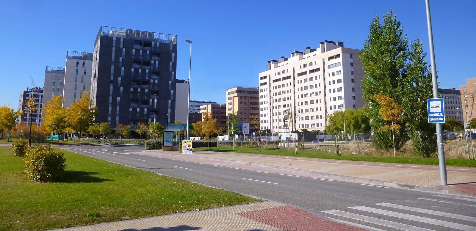 Calle de Sarriguren (Valle de Egüés) con bloques de viviendas recientes, césped y árboles con colores de otoño