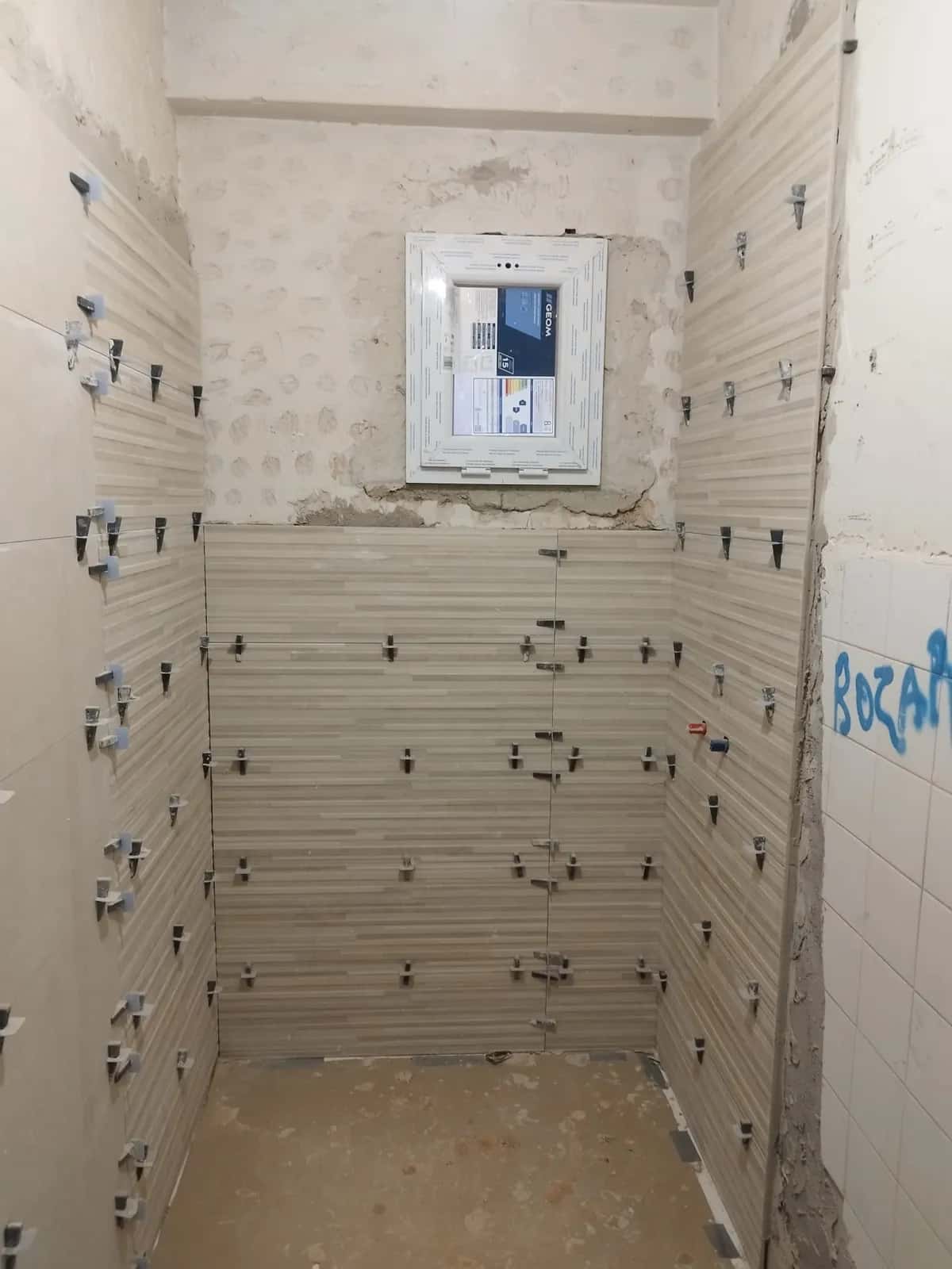 Baño en obra con azulejos nuevos colocados con crucetas niveladoras