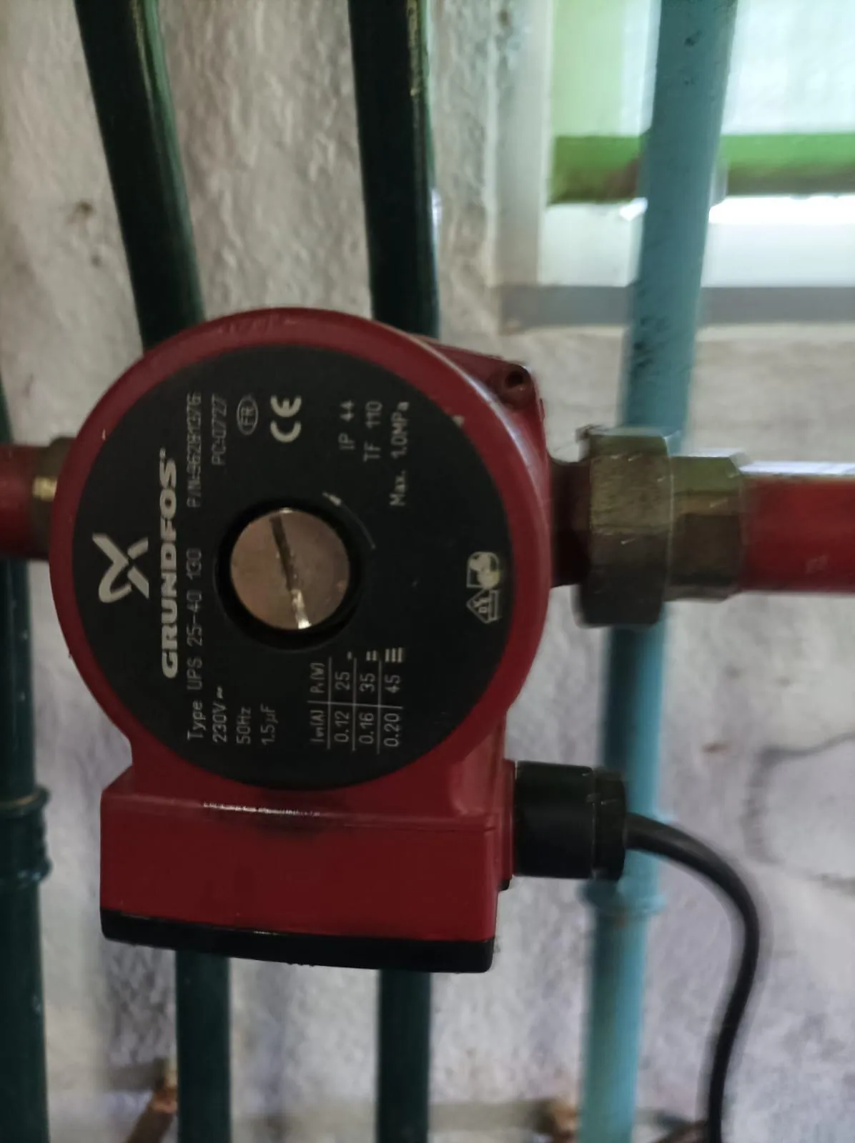Bomba circuladora de calefacción instalada entre tuberías pintadas de rojo y verde