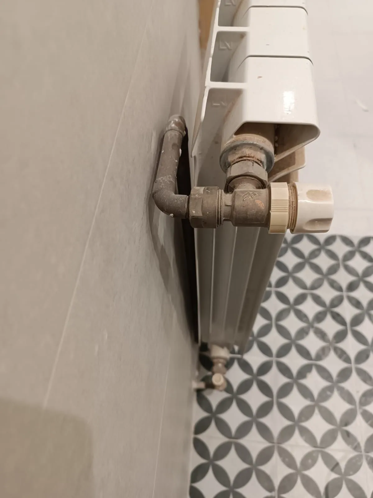 Detentor y tubería de conexión de un radiador de aluminio junto a la pared