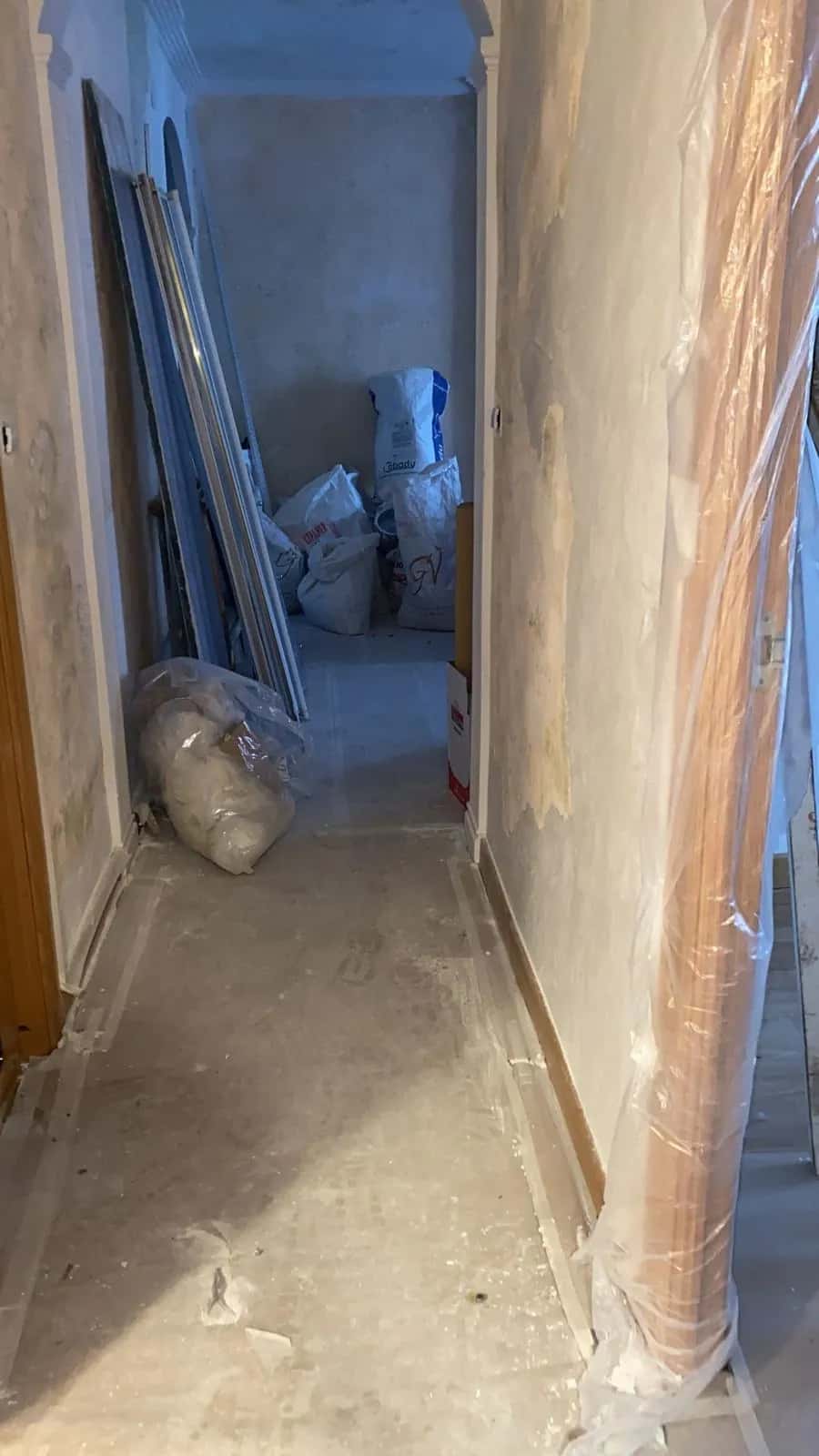 Pasillo protegido con plástico y sacos de escombro durante una reforma