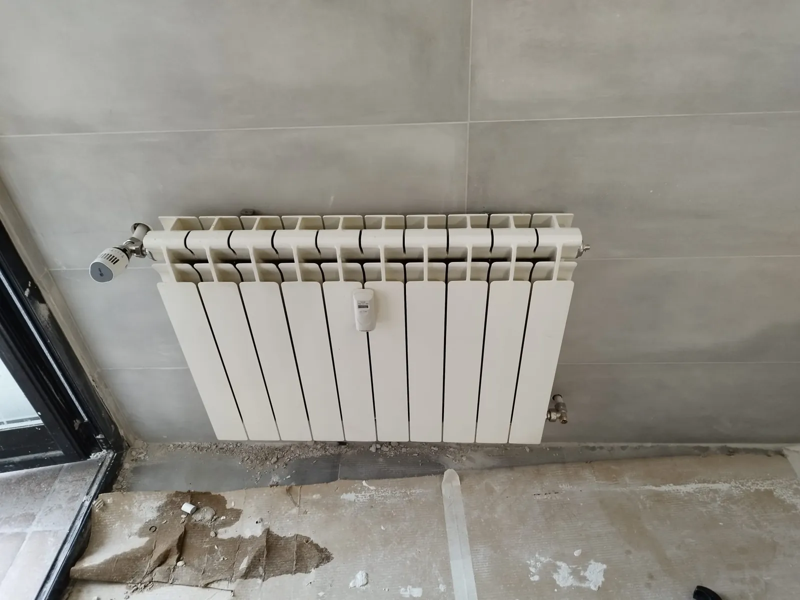 Radiador de aluminio con válvula termostática recién instalado en una vivienda en obra